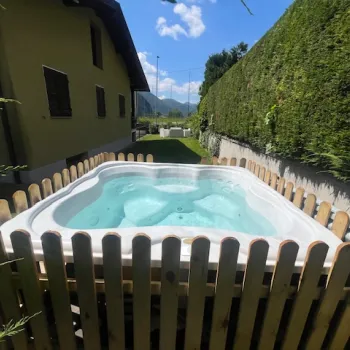 Hot tub in a garden, surrounded by a wooden fence, sunny day.