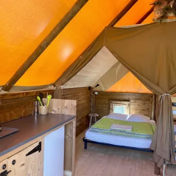 Glamping tent's living room with kitchen and double bed in the backgroung