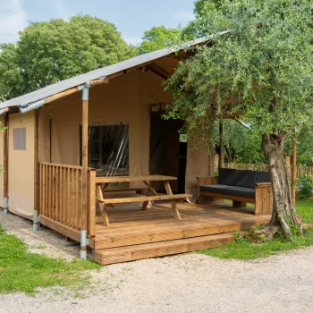 Cabin with a wooden deck, picnic table, and trees nearby.
