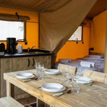 Rustic tent interior with kitchen and dining table setup.