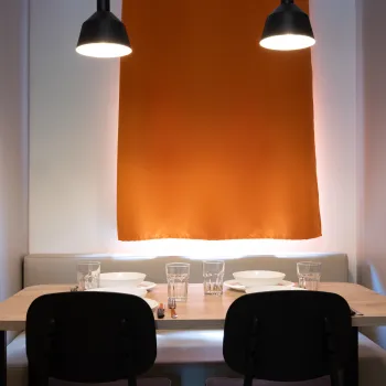 Cozy dining area with an orange curtain and black pendant lights.