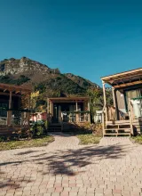 Cabins with wooden porches, mountain backdrop, clear sky.