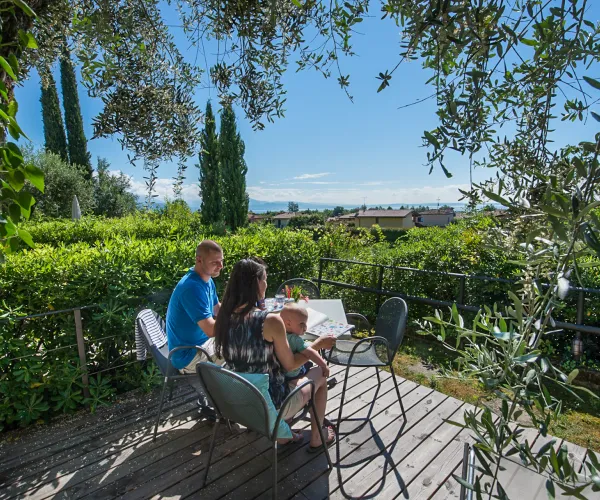 Couple dining on a leafy terrace, scenic countryside view.