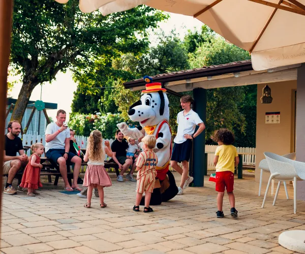 Children interacting with a costumed character outdoors, sunny day.