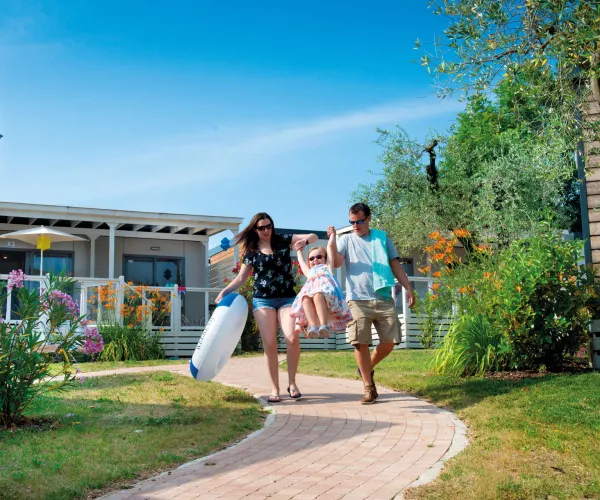 Family walking along a garden path under a clear blue sky.
