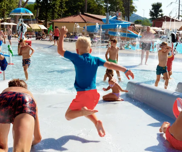 Children playing and splashing in a sunny water park.