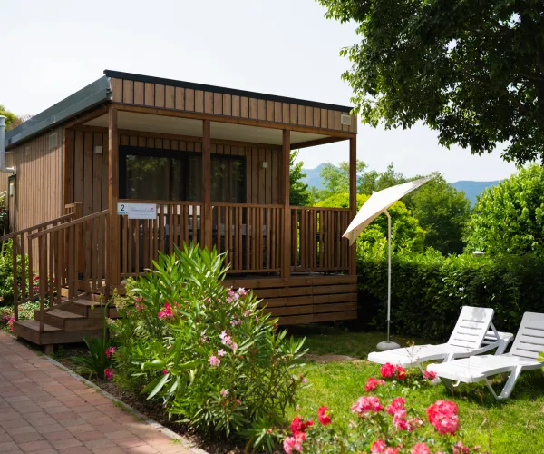 Weekend Loggia with chairs and umbrella in a garden setting.