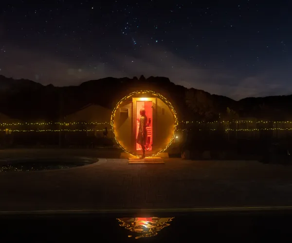 Red-lit phone booth in a starry night landscape, surrounded by mountains.