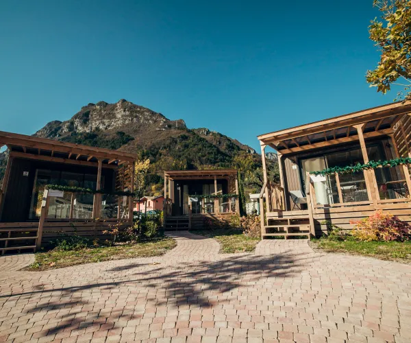 Cabins with wooden porches, mountain backdrop, clear sky.