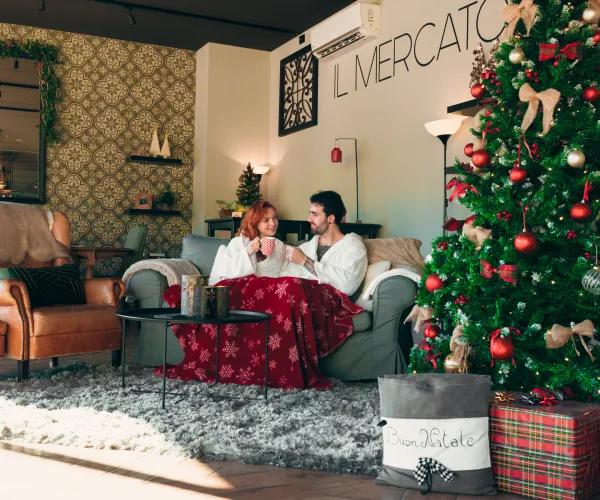 Cozy couple by Christmas tree in warm, festive living room.