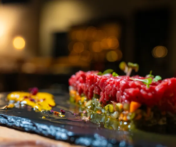 Tuna tartare with herbs on a slate plate in dim lighting.