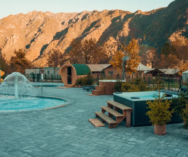 Mountain resort with fountain, hot tub, and cabins at sunset.