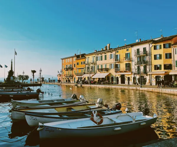 Boats on a calm canal beside colorful buildings under a clear blue sky.