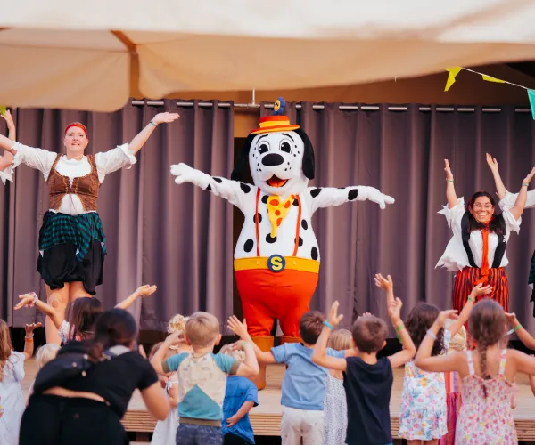 Children dance with performers and a Dalmatian mascot on stage.