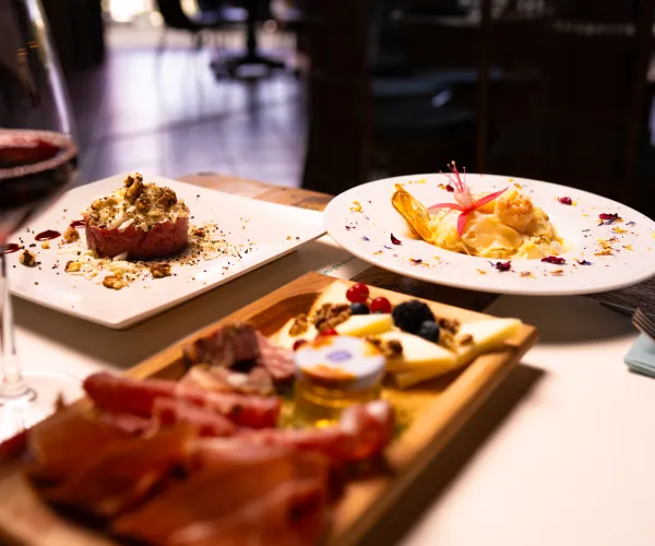 Gourmet dishes and red wine on a restaurant table.