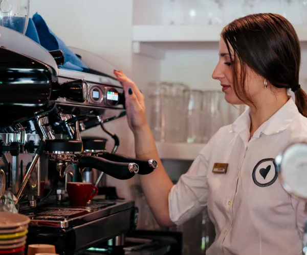 Barista operating an espresso machine in a cafe.
