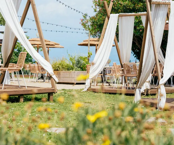 Outdoor cafe with draped canopies, wooden chairs, and string lights.