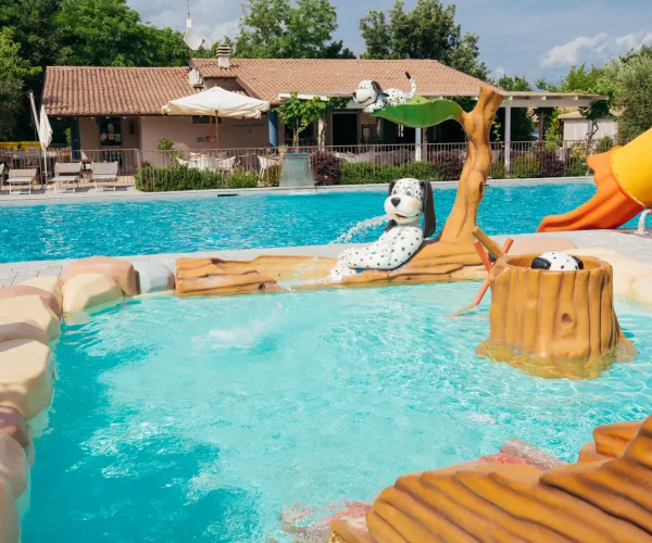 Children's pool with water slide and playful cow statue.