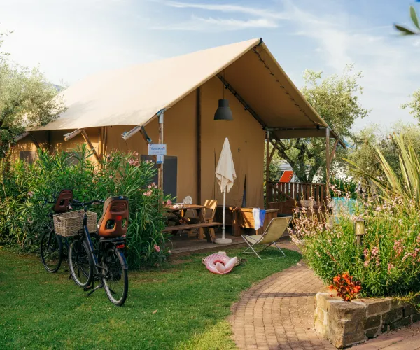 Cozy canvas tent surrounded by lush greenery and a bicycle parked nearby.