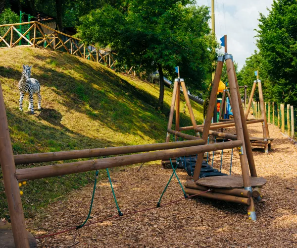 Outdoor play area with wooden structures and a grassy hill.