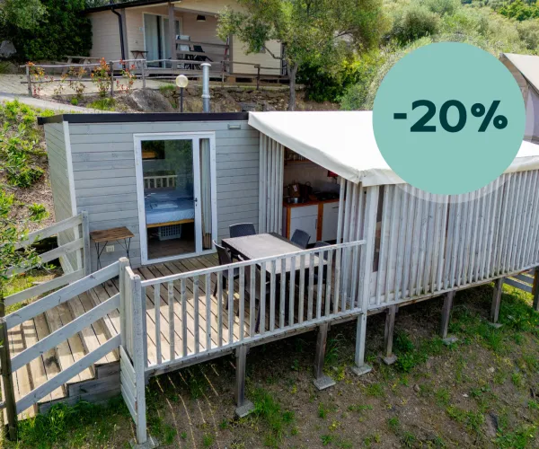 Small cabin with deck in a wooded area, discount badge displayed.