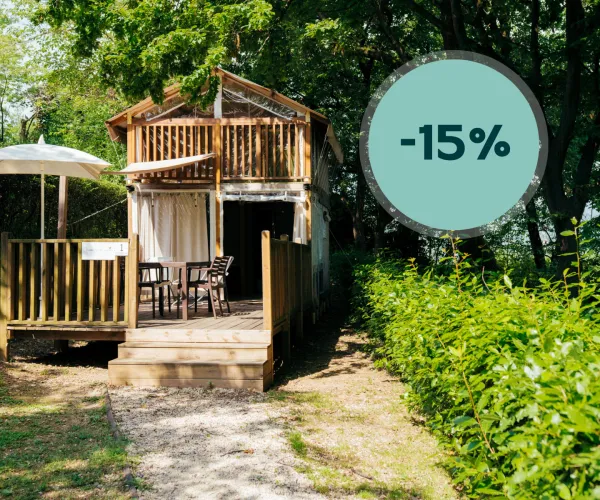 Two-story wooden cabin with patio, surrounded by lush greenery, discount tag shown.