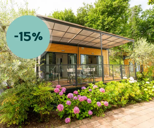 Modern house with a veranda, surrounded by lush greenery and flowers.