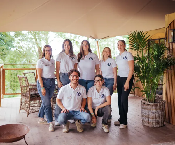 Team of seven in matching shirts on a wooden deck with tropical decor.