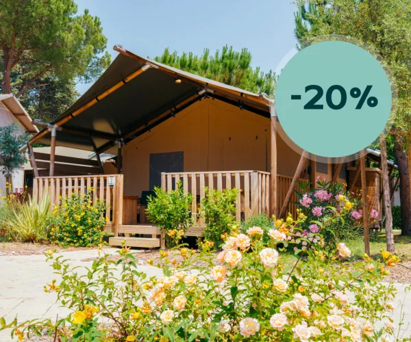 Rustic cabin with wooden porch amidst blooming flowers, sunny day.
