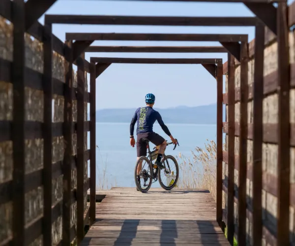 A cyclist pauses on a wooden pathway by Lake Trasimeno in Umbria.