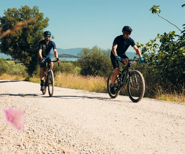 Cyclists riding on a gravel path under a clear blue sky.